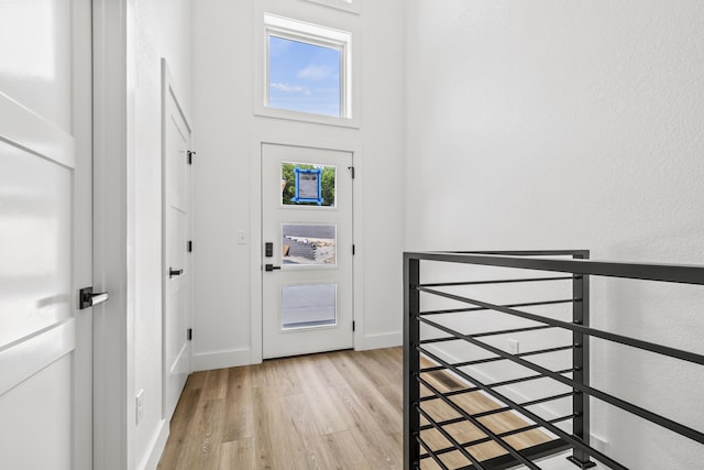 foyer entrance with a high ceiling, light wood-style flooring, and baseboards