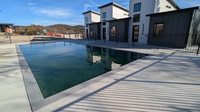 pool featuring a patio area, fence, and a mountain view