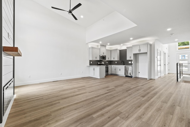 unfurnished living room with light wood-style floors, a ceiling fan, a sink, and recessed lighting