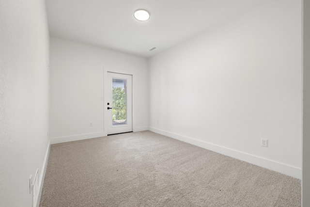 spare room featuring carpet floors, visible vents, and baseboards