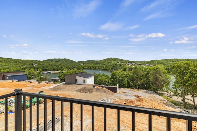 exterior space with a water view, a balcony, and a forest view