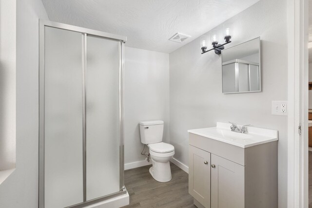 bathroom with toilet, wood finished floors, visible vents, vanity, and a shower stall