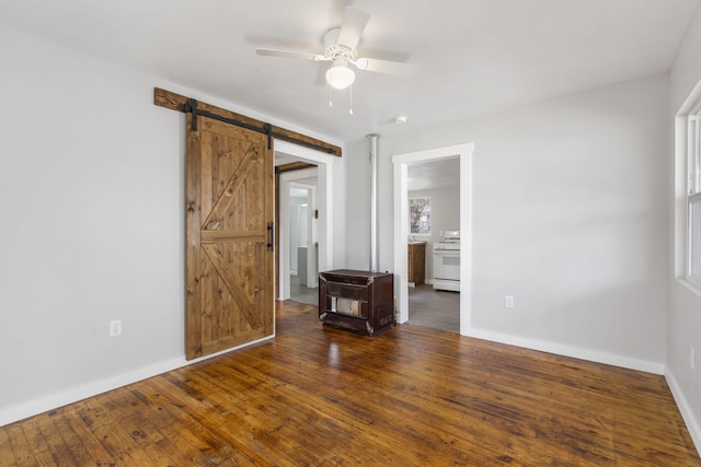 unfurnished room featuring a barn door, baseboards, ceiling fan, and hardwood / wood-style floors