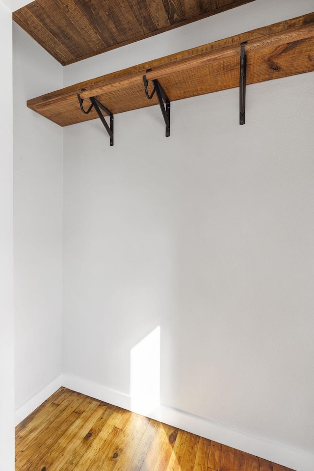 walk in closet featuring beam ceiling and hardwood / wood-style floors