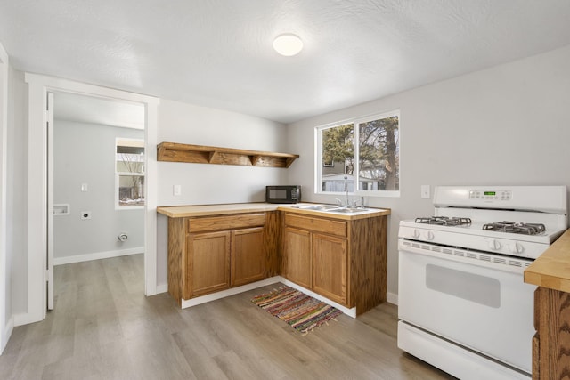 kitchen with a wealth of natural light, black microwave, open shelves, and gas range gas stove