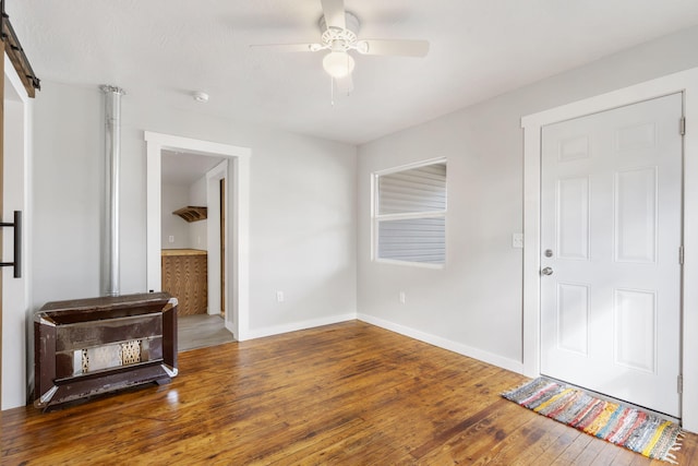 interior space featuring hardwood / wood-style flooring, ceiling fan, baseboards, and a barn door