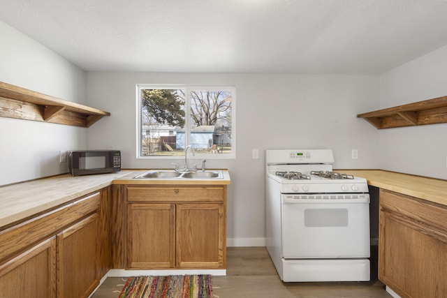 kitchen featuring butcher block counters, white gas stove, black microwave, open shelves, and a sink