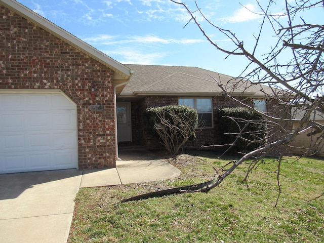 ranch-style home featuring an attached garage, a shingled roof, a front yard, and brick siding