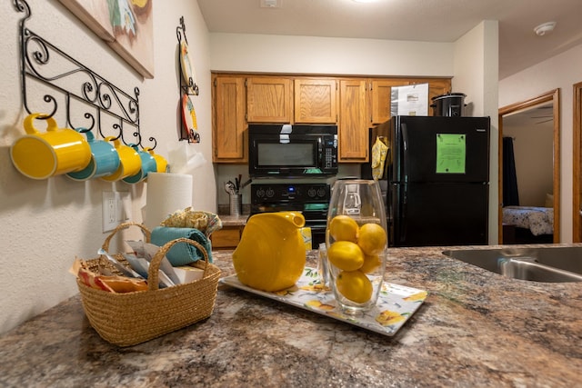 kitchen featuring brown cabinetry, dark countertops, and black appliances