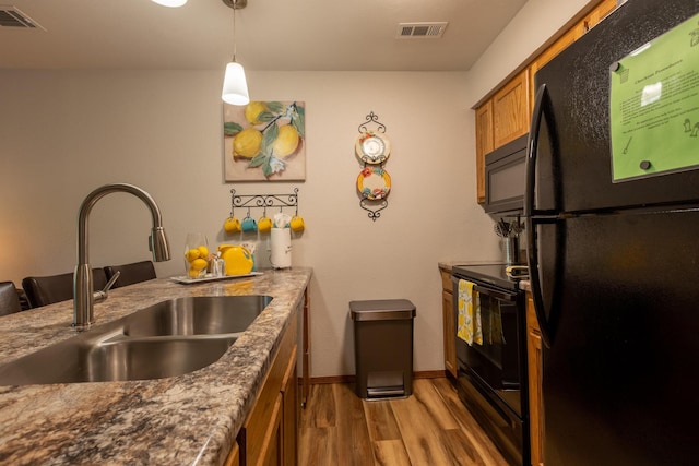 kitchen featuring black appliances, visible vents, brown cabinets, and a sink