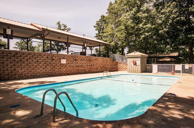 view of swimming pool featuring fence, an outdoor structure, a fenced in pool, and a patio