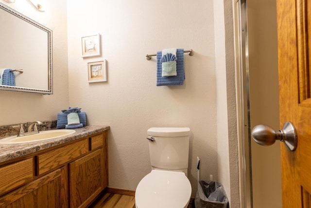 bathroom with baseboards, vanity, toilet, and wood finished floors