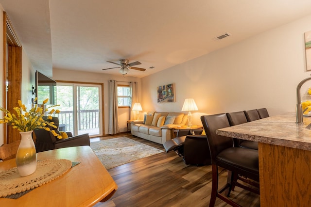 living room with ceiling fan, dark wood-type flooring, and visible vents