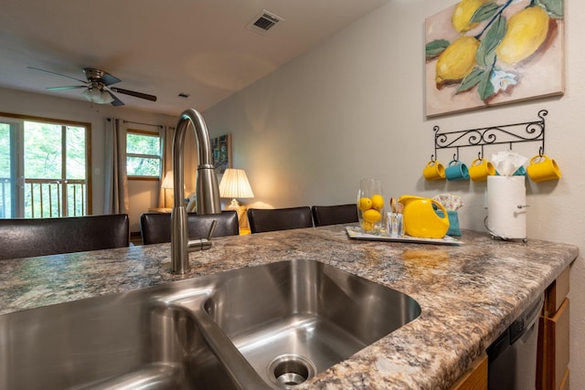 interior details featuring stone counters, a sink, visible vents, a ceiling fan, and dishwasher