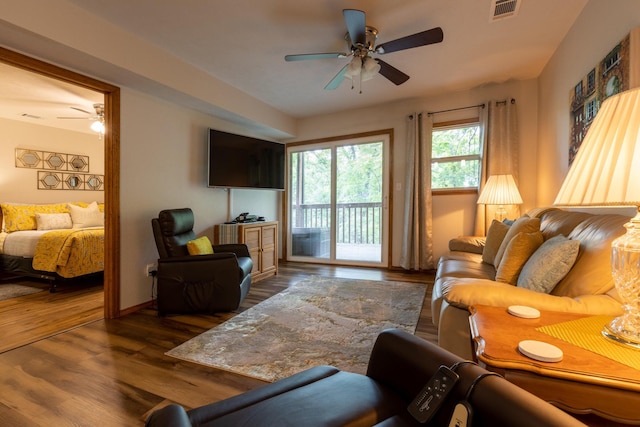 living area featuring visible vents, ceiling fan, baseboards, and wood finished floors