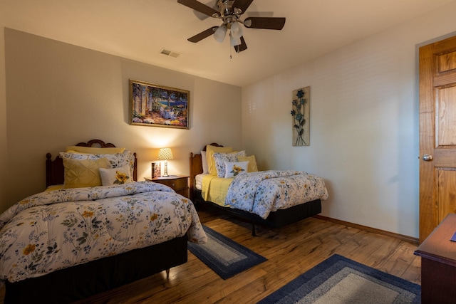 bedroom with a ceiling fan, wood-type flooring, visible vents, and baseboards