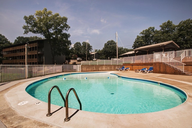 pool with stairs, a patio area, and fence