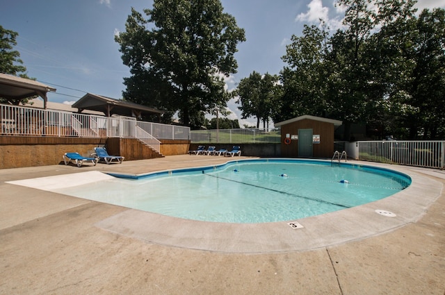 pool with a patio area and fence