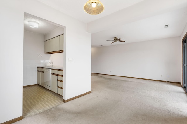 interior space featuring tile walls, light countertops, light carpet, ceiling fan, and dishwasher