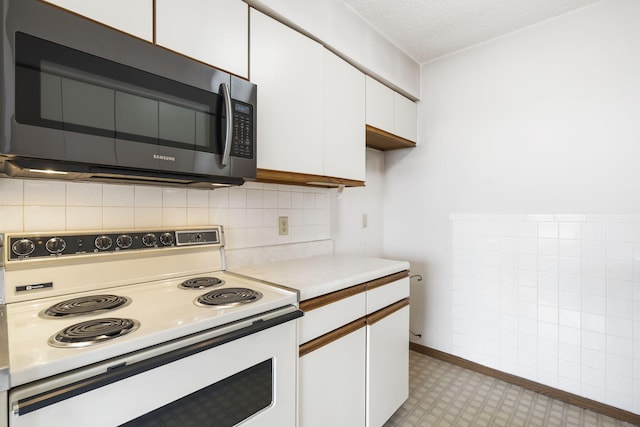 kitchen featuring electric range, white cabinets, stainless steel microwave, light countertops, and a textured ceiling