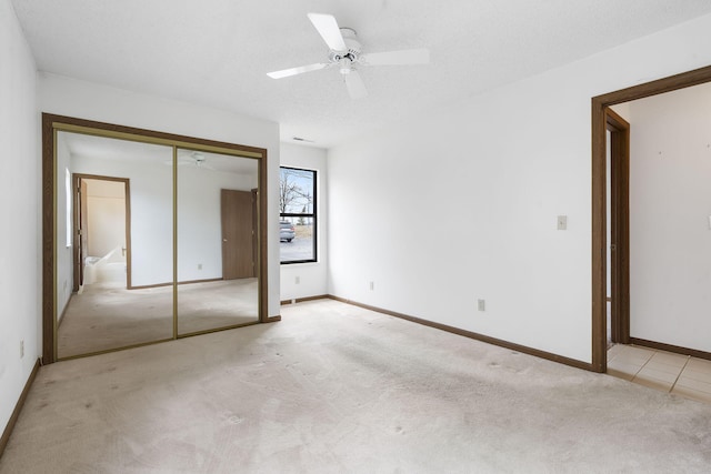 unfurnished bedroom with a closet, light colored carpet, a textured ceiling, and baseboards