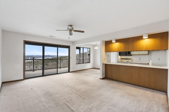 kitchen featuring light carpet, stainless steel microwave, brown cabinets, light countertops, and white electric range