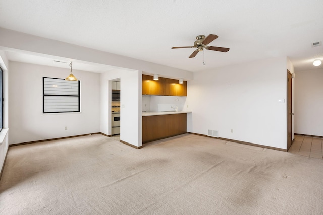 unfurnished living room with light carpet, ceiling fan, visible vents, and baseboards