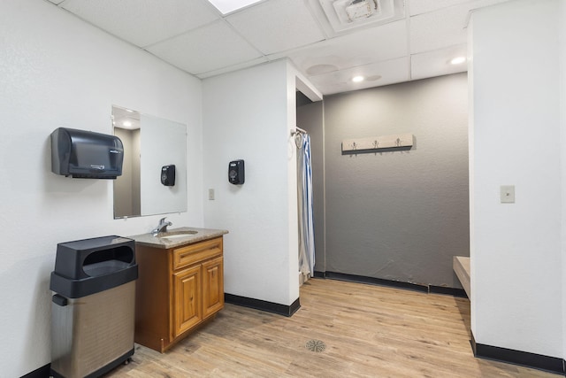 bathroom featuring curtained shower, a drop ceiling, wood finished floors, vanity, and baseboards