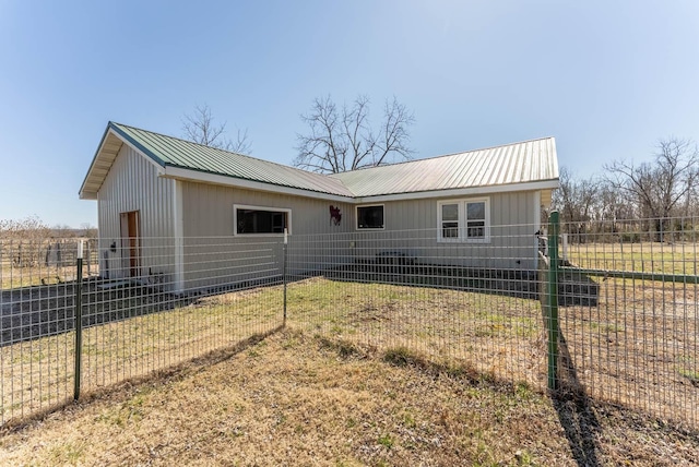 exterior space featuring metal roof, a front lawn, and fence