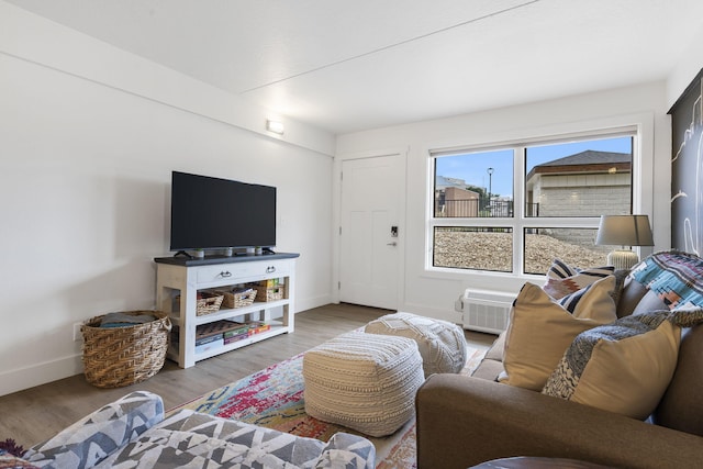 living room with an AC wall unit, wood finished floors, and baseboards