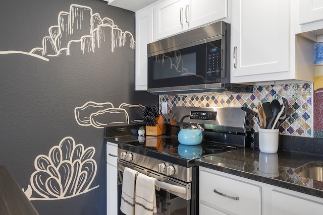 kitchen with a textured wall, stainless steel appliances, white cabinets, backsplash, and dark stone counters