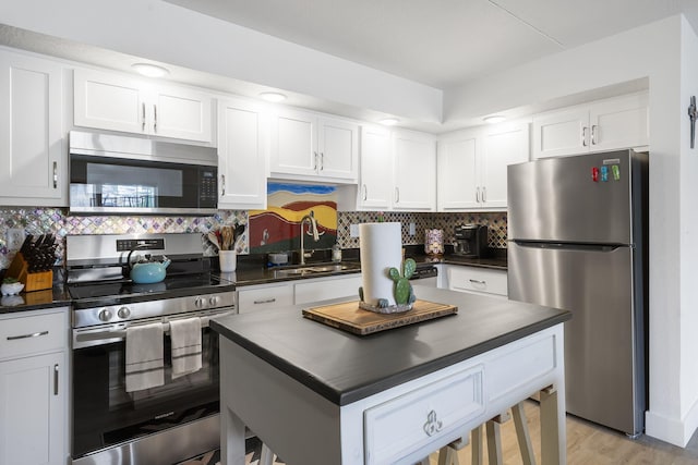 kitchen with stainless steel appliances, dark countertops, and a sink