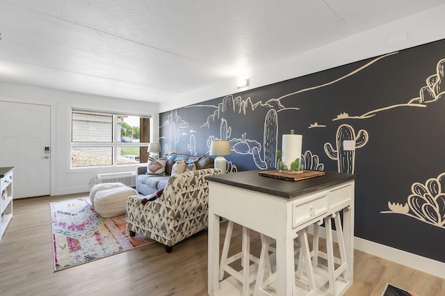 living room featuring light wood finished floors, an accent wall, and baseboards