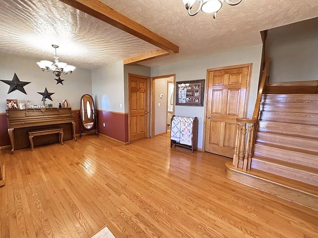 interior space with a chandelier, light wood-style flooring, a textured ceiling, and stairs