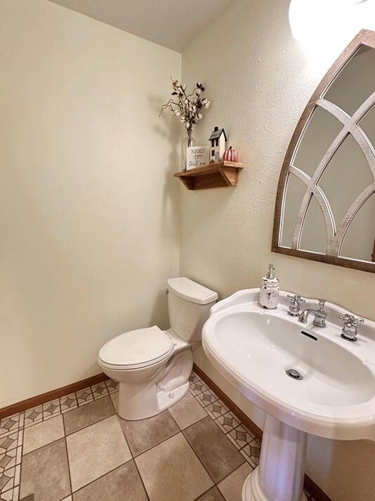 bathroom featuring a sink, tile patterned floors, toilet, and baseboards