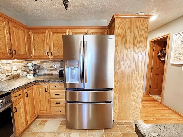 kitchen featuring tasteful backsplash, appliances with stainless steel finishes, a textured ceiling, and stone finish flooring