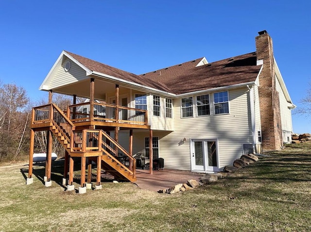 rear view of property featuring a patio, a chimney, a shingled roof, a lawn, and stairway