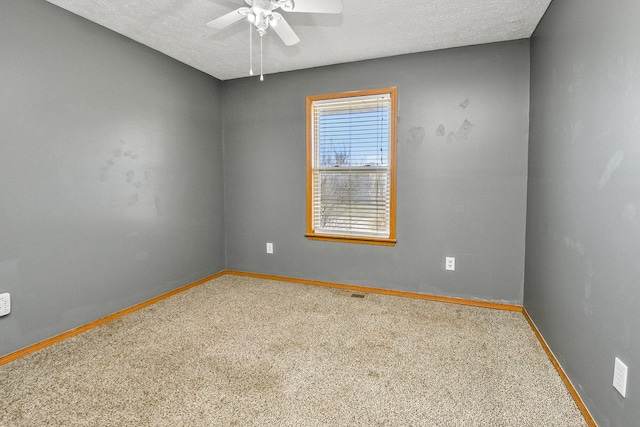 carpeted empty room with a textured ceiling, ceiling fan, visible vents, and baseboards