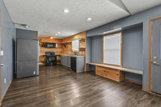 kitchen featuring dark wood finished floors, light countertops, a sink, a textured ceiling, and black appliances