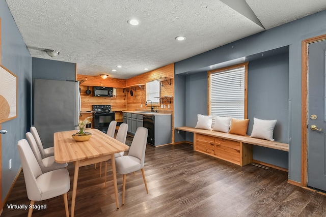 dining area with wood walls, a textured ceiling, dark wood-type flooring, and recessed lighting