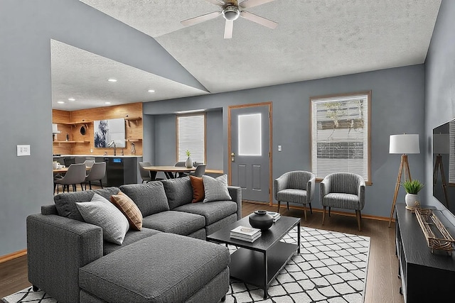 living room featuring lofted ceiling, light wood-style flooring, baseboards, and a textured ceiling