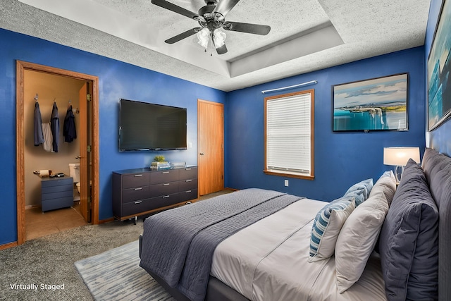 bedroom featuring a textured ceiling, ensuite bathroom, carpet flooring, baseboards, and a raised ceiling