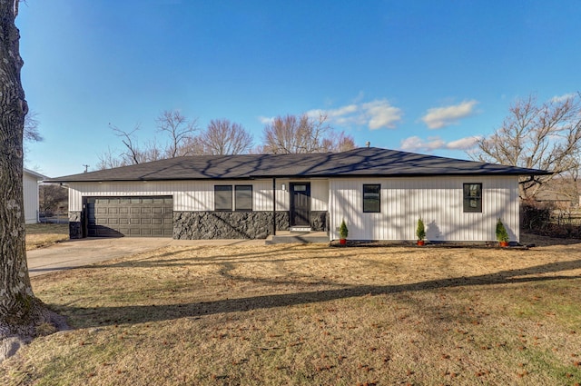 back of property featuring concrete driveway, a lawn, and an attached garage