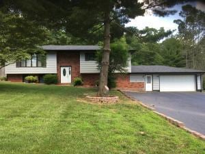 split foyer home with a garage, aphalt driveway, and a front yard