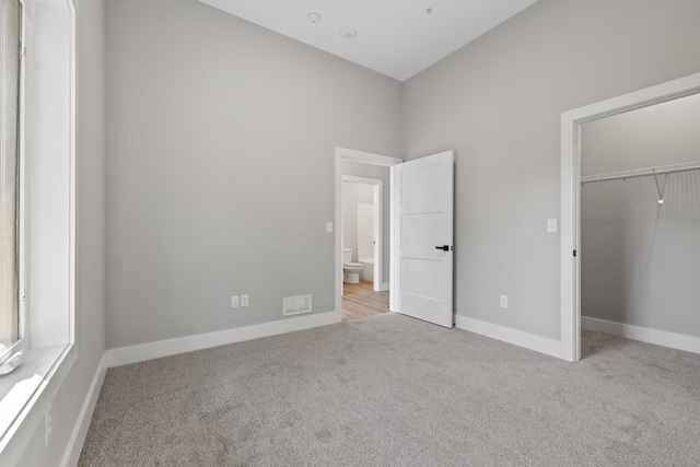 unfurnished bedroom with a closet, carpet, visible vents, and baseboards