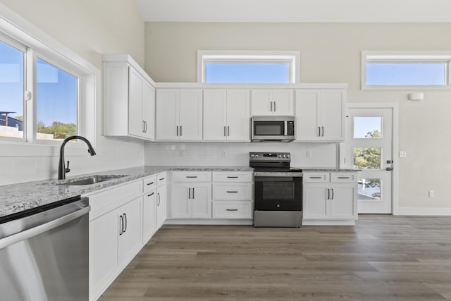 kitchen with wood finished floors, appliances with stainless steel finishes, a sink, and white cabinetry