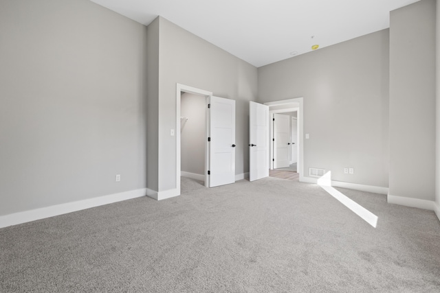 unfurnished bedroom featuring light carpet, a spacious closet, visible vents, and baseboards