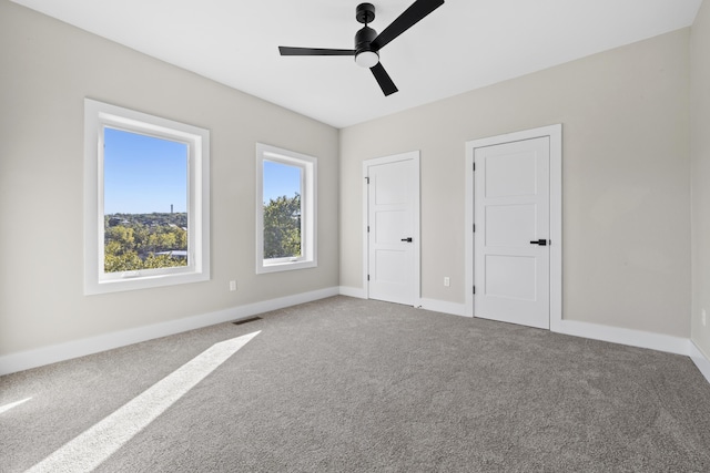 unfurnished bedroom featuring carpet floors, baseboards, visible vents, and ceiling fan