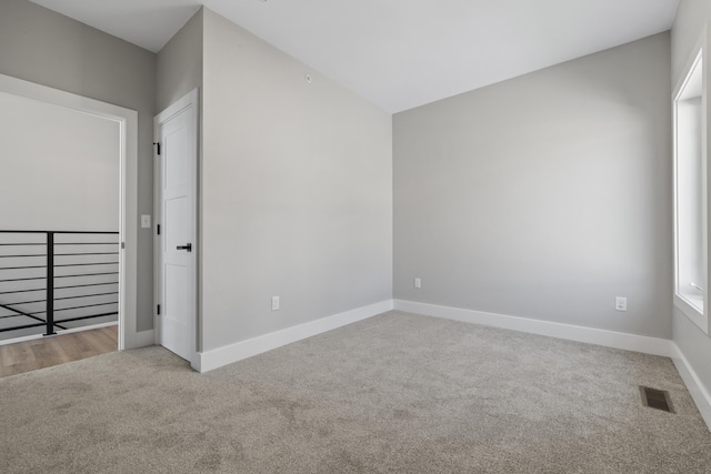 empty room featuring carpet floors, visible vents, and baseboards