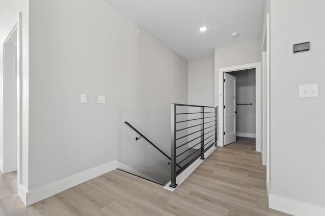 hallway with light wood finished floors, an upstairs landing, and baseboards